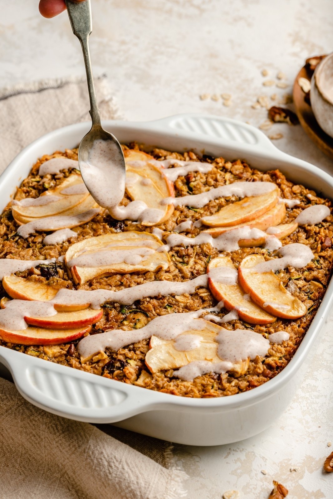 drizzling an apple zucchini oatmeal bake with a glaze